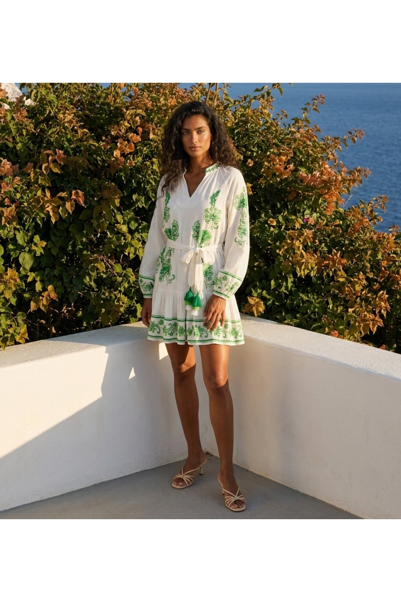Vestido curto branco manga comprida com bordado floral verde, decote em V, cintura amarrada com borlas e saia em camadas.