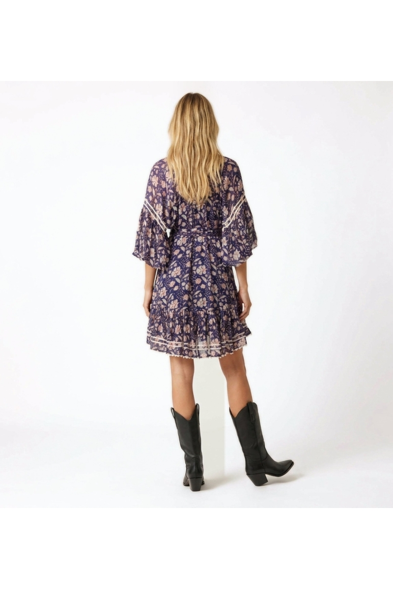 Vue dos d'une mini-robe fluide bleu marine à fleurs roses/blanches, manches ballon, col V, jupe à volants et ceinture.