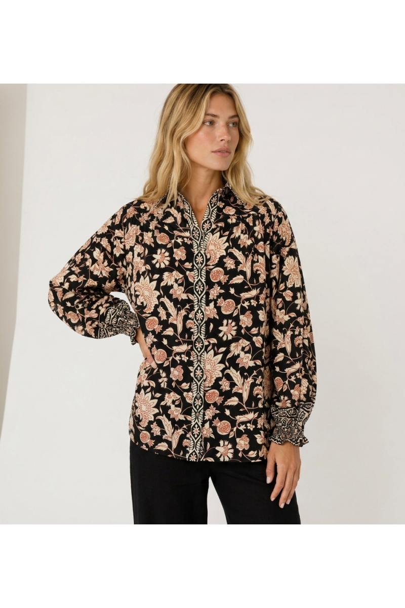 Blusa nera a maniche lunghe con fantasia floreale crema e ruggine, collo e polsini a balze in tessuto leggero.