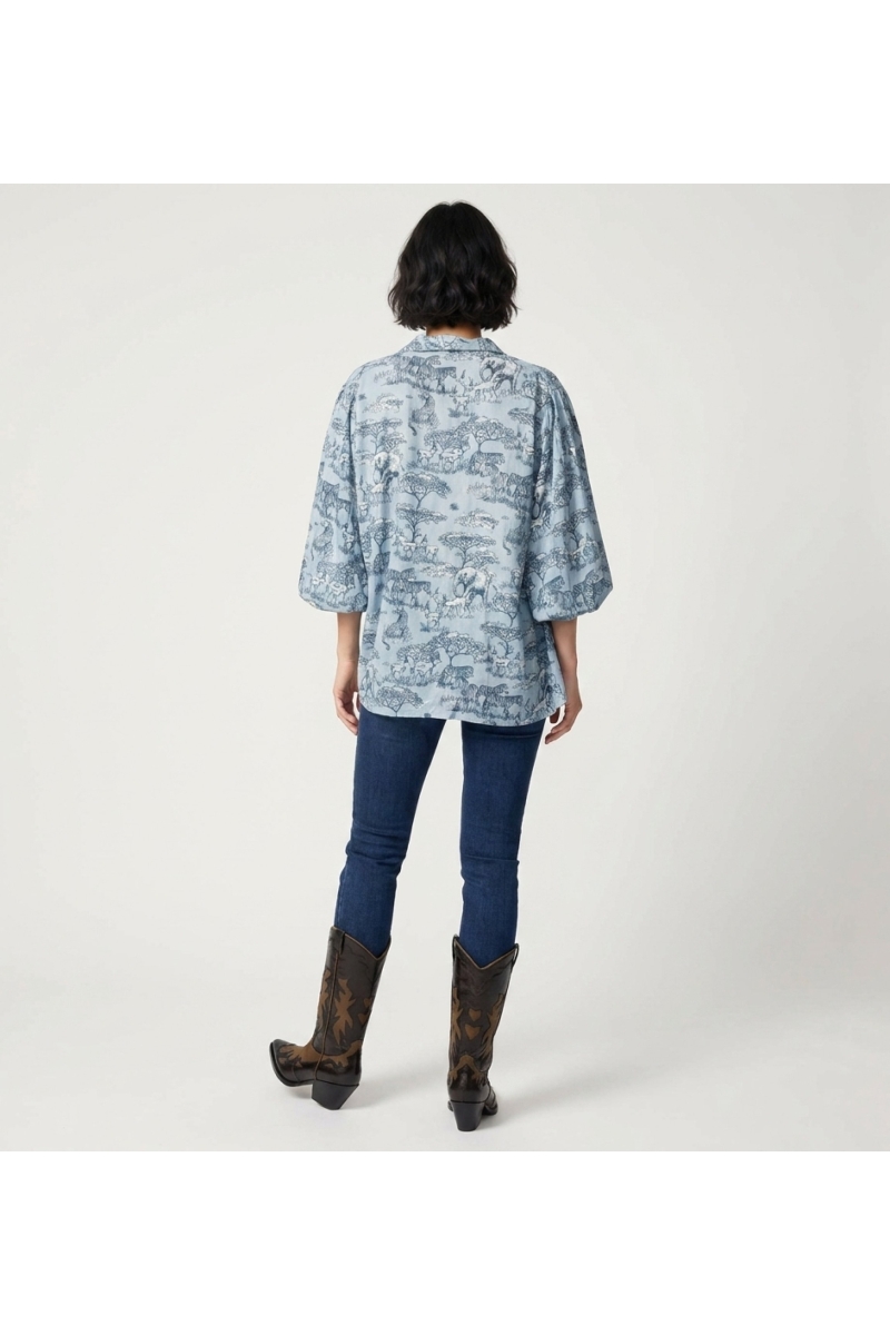 Light blue long-sleeve button-up shirt, back view. Features dark blue/white safari animal print, puffed shirred cuffs.