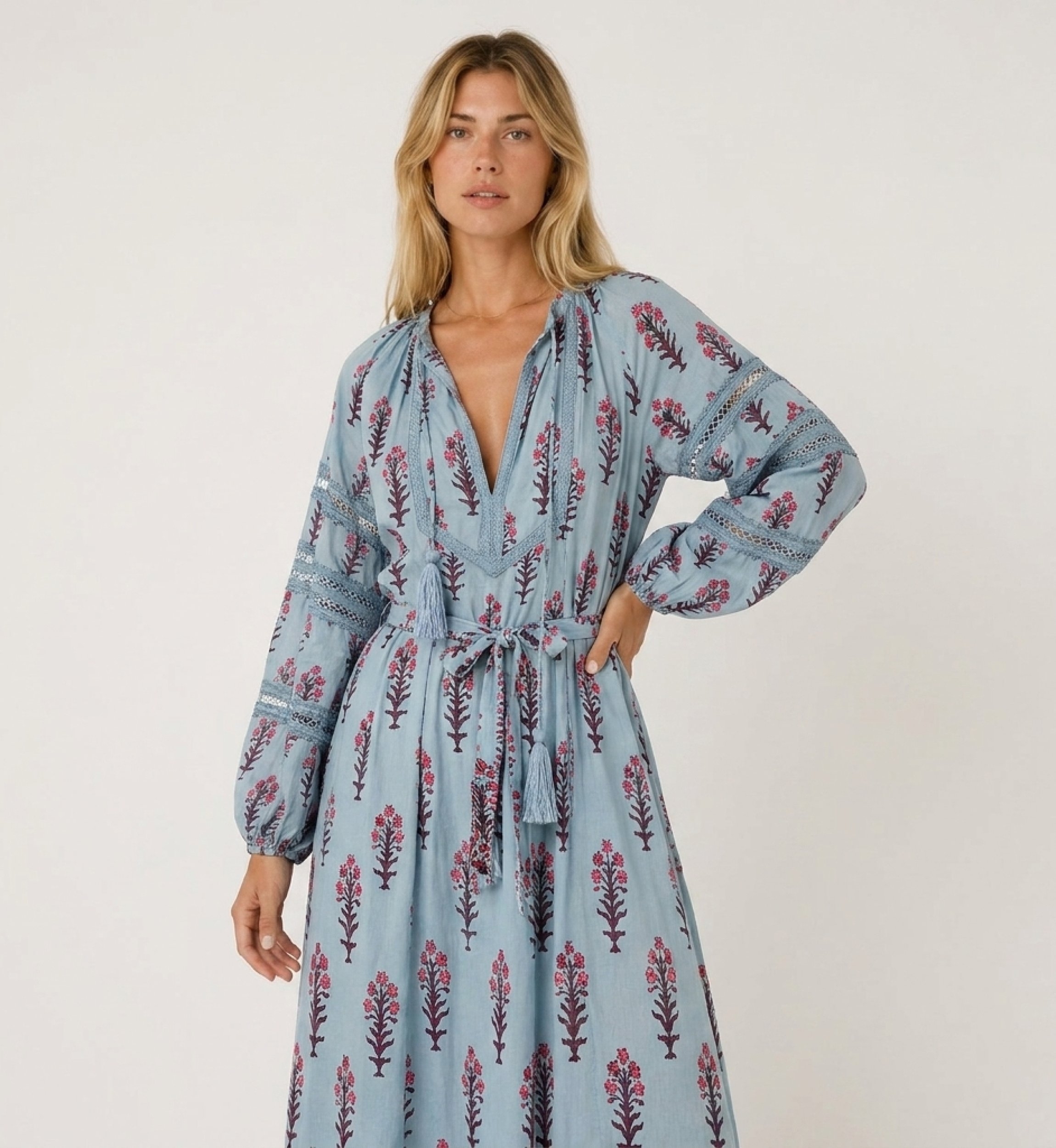 Vestito midi azzurro a fiori, vista tre quarti. Maniche lunghe a palloncino, scollo a V, vita annodata con nappe.