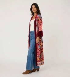 Three-quarter view of a long, loose burgundy kimono with vibrant floral & paisley pattern, dark red velvet trim.