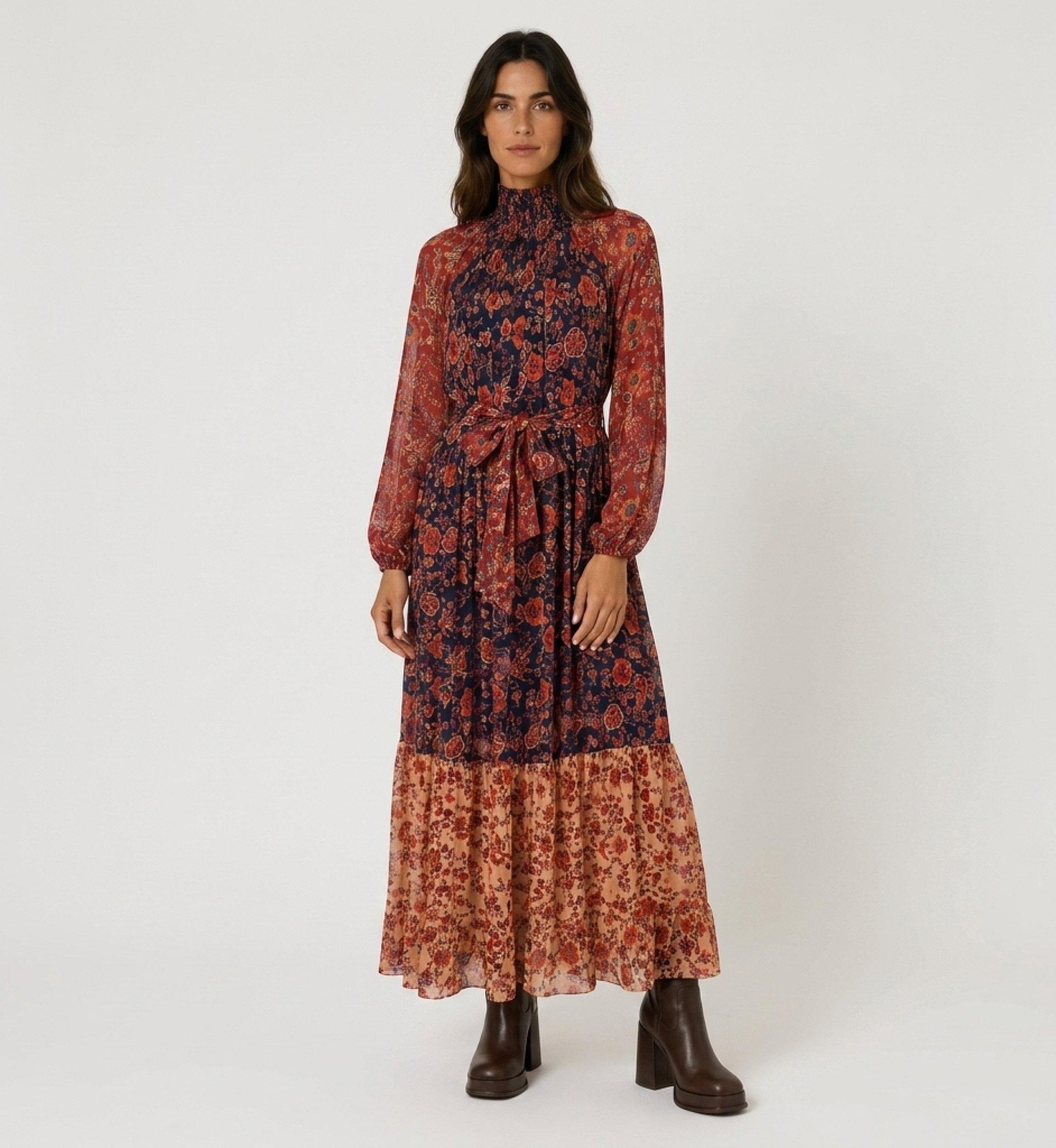 Front view of a sheer tiered maxi dress with floral pattern in red, orange & navy, smocked high neck & balloon sleeves.