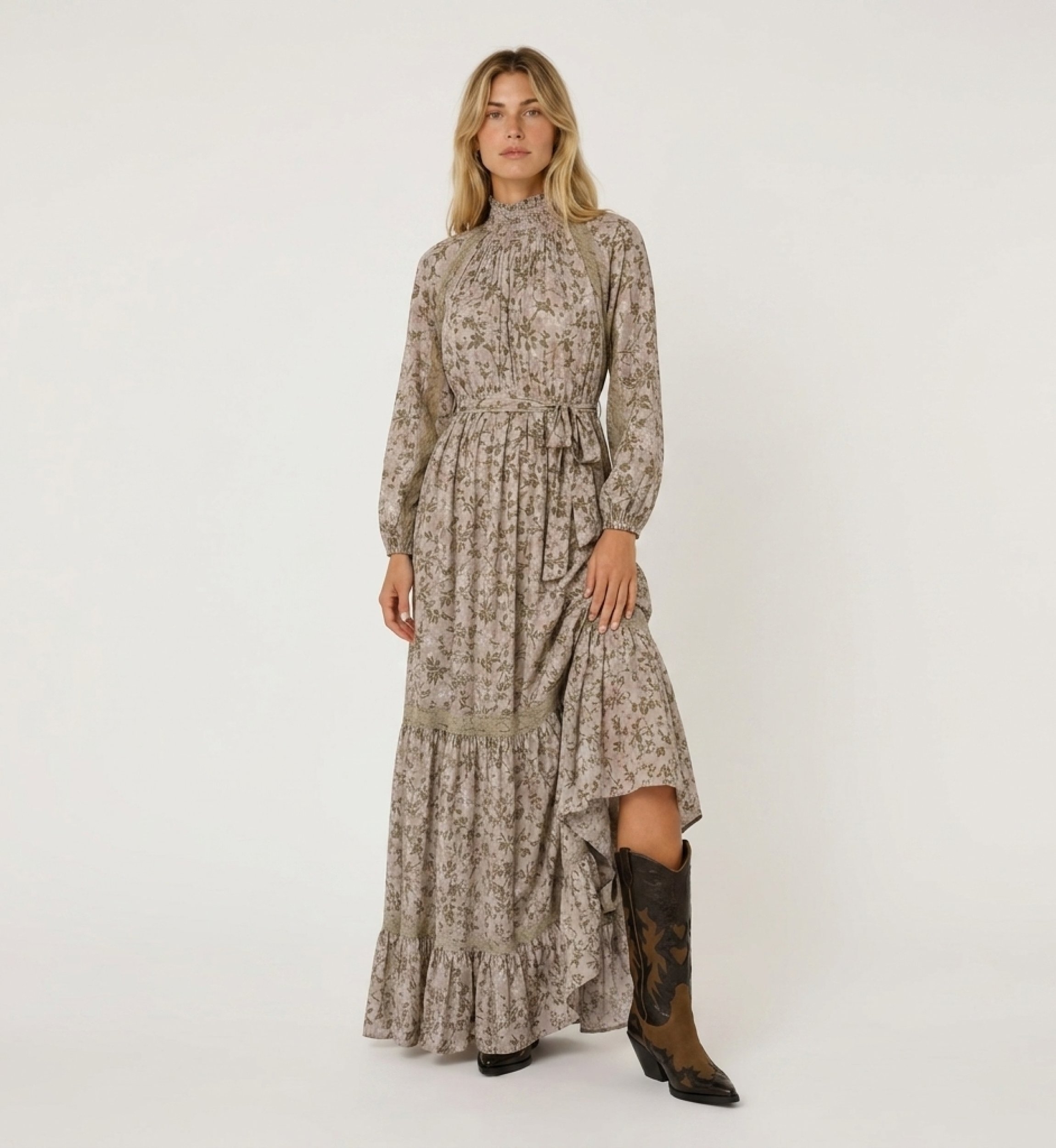 Front view of a light pink floral maxi dress with green gold leaf patterns, high smocked neck, puff sleeves, and lace trim.