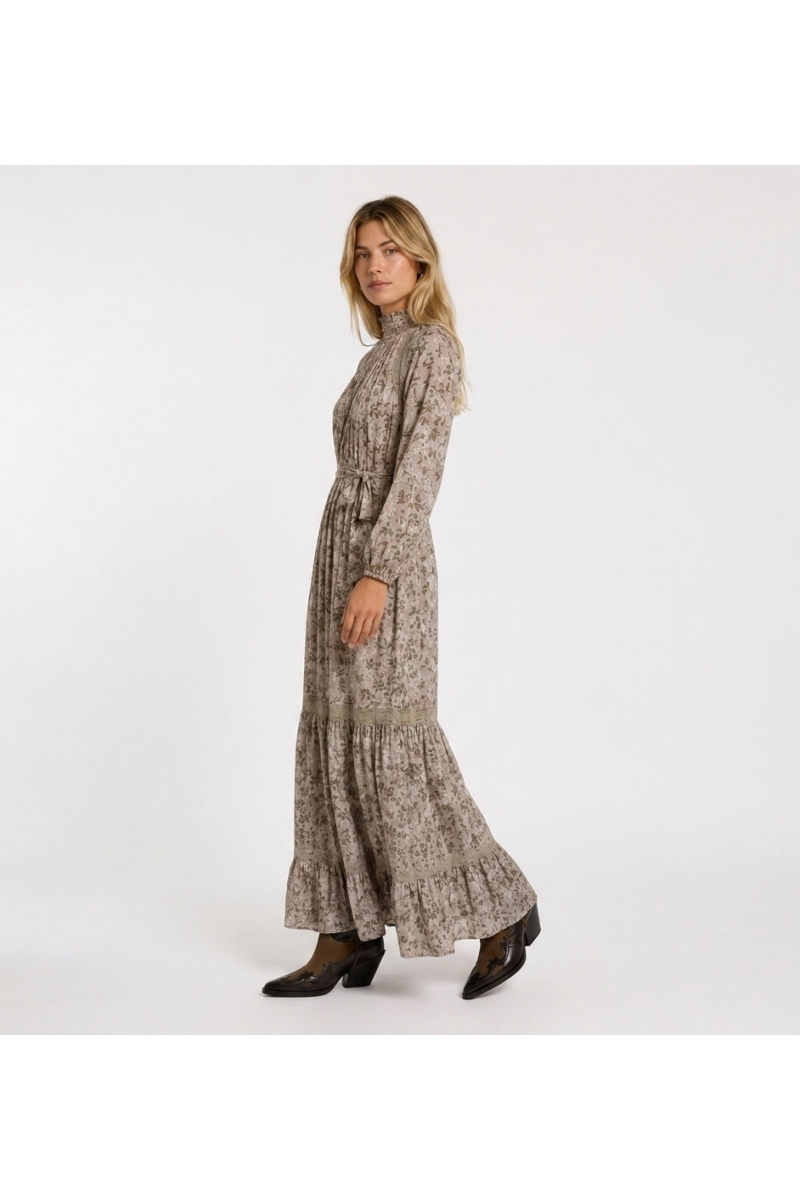 Vestido maxi longo rosa claro floral com folhas verdes douradas, gola smock alta, mangas bufantes e detalhes de renda.