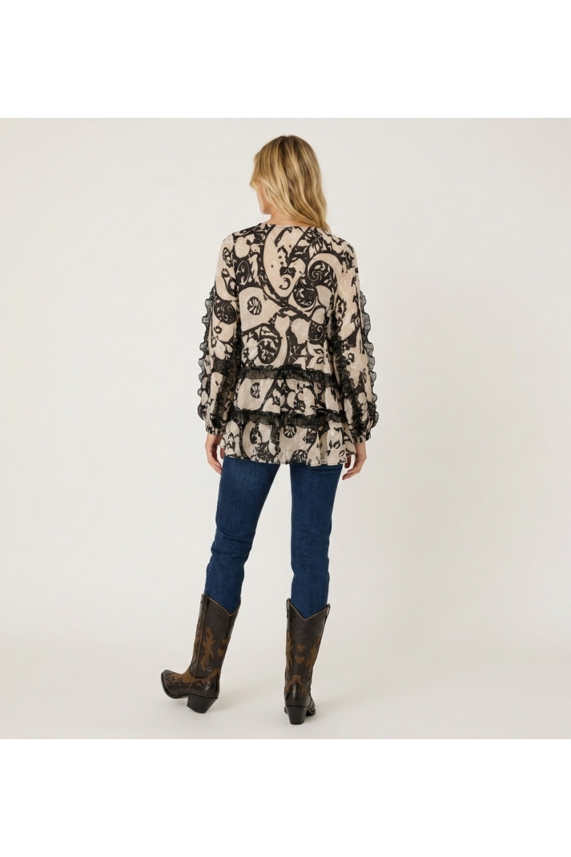 Blusa leggera fantasia beige e nera, maniche lunghe, vestibilità ampia con ruches e nappine, vista dietro.