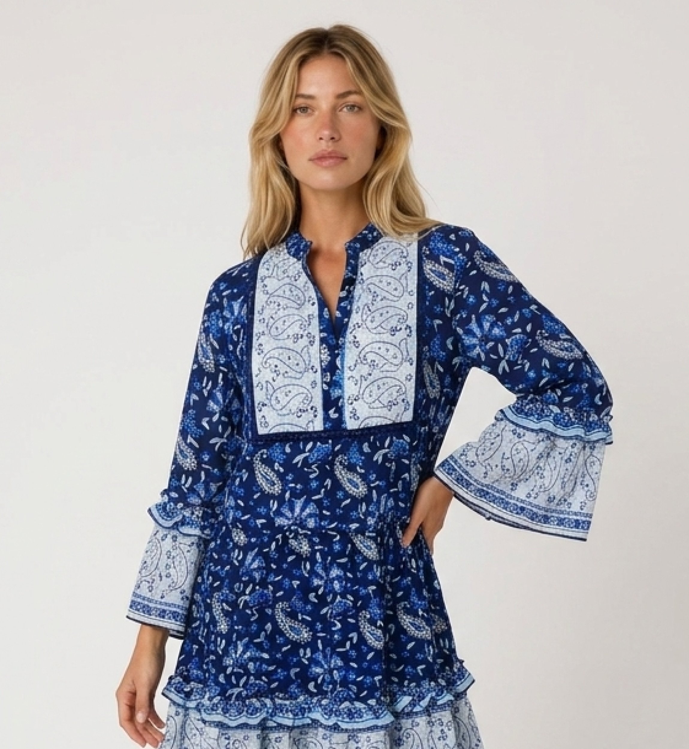 Blue and white paisley floral mini dress, collared V-neck, three-quarter ruffled sleeves, tiered skirt, side view.