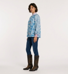 Blusa blu a maniche lunghe con fantasia floreale rosa e bianca, collo alto, vestibilità ampia, tessuto cotone, vista laterale 3/
