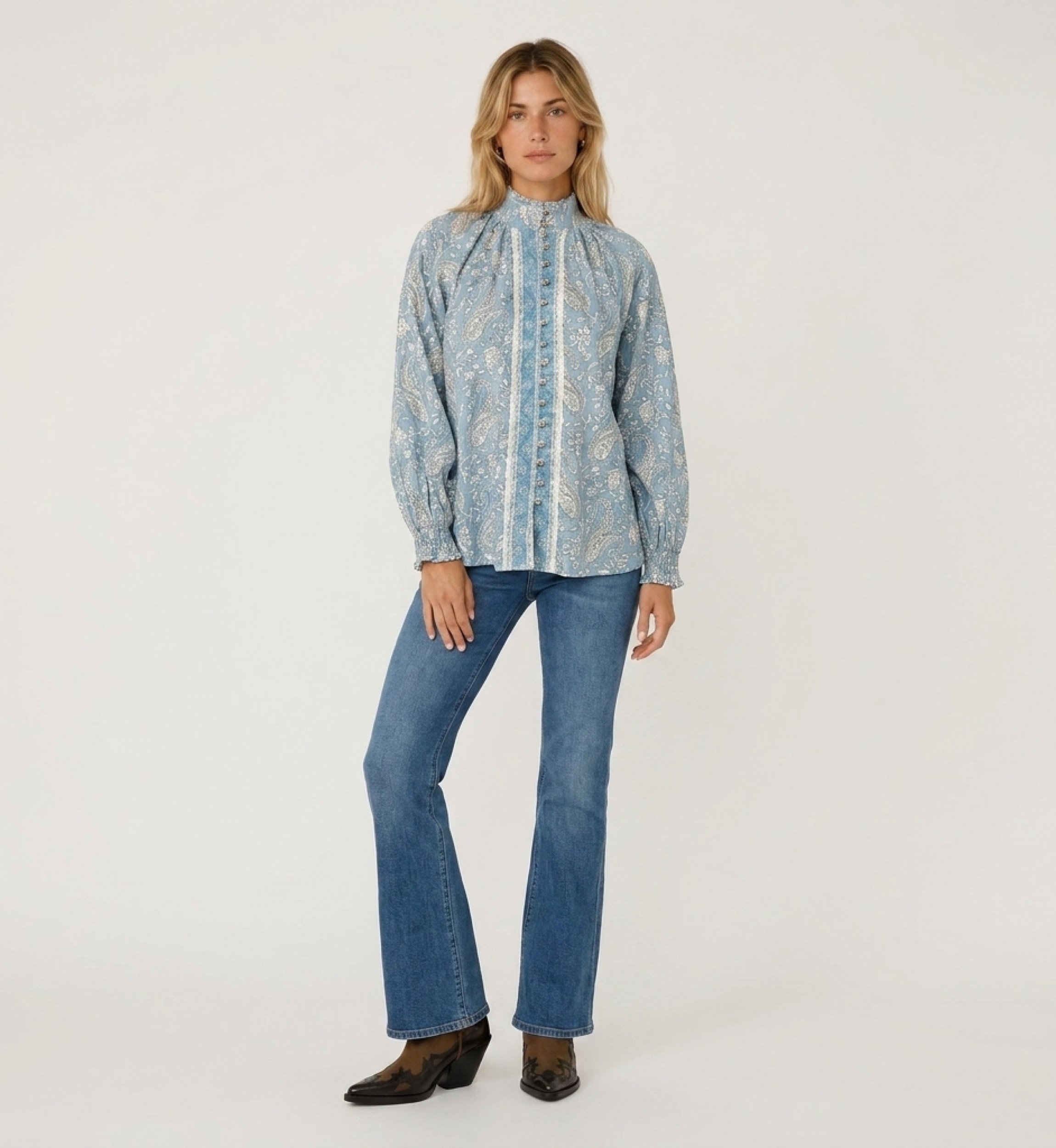 Front view of a light blue long-sleeve blouse with white paisley pattern, high collar, button-down front, and ruffled cuffs.