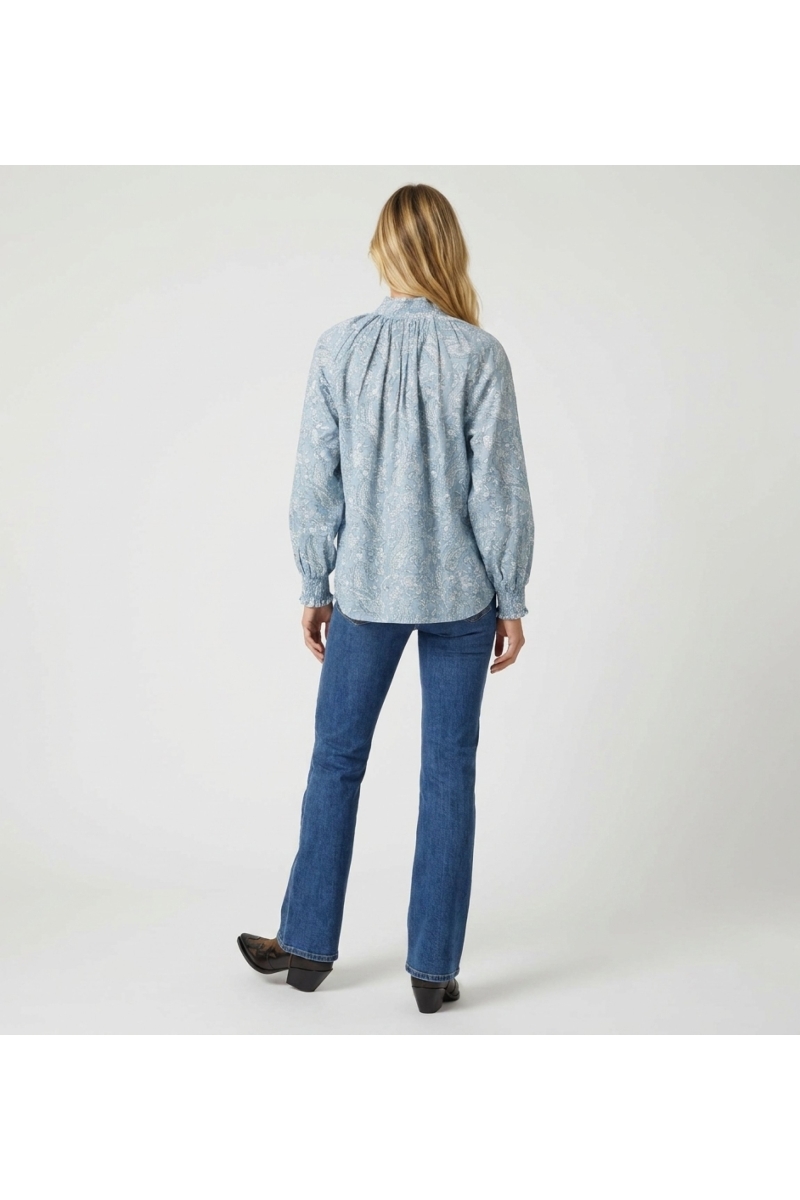 Chemisier bleu clair à manches longues motif cachemire blanc, col montant, poignets volantés, vue dos. Élégante blouse boutonnée