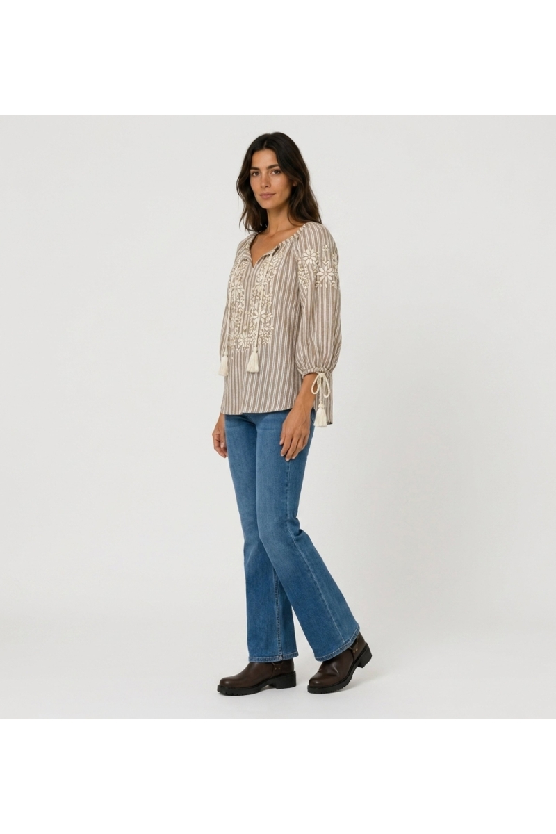 Blusa camponesa listrada marrom e branca, decote V, manga balão 3/4, bordado floral, borlas. Vista lateral.