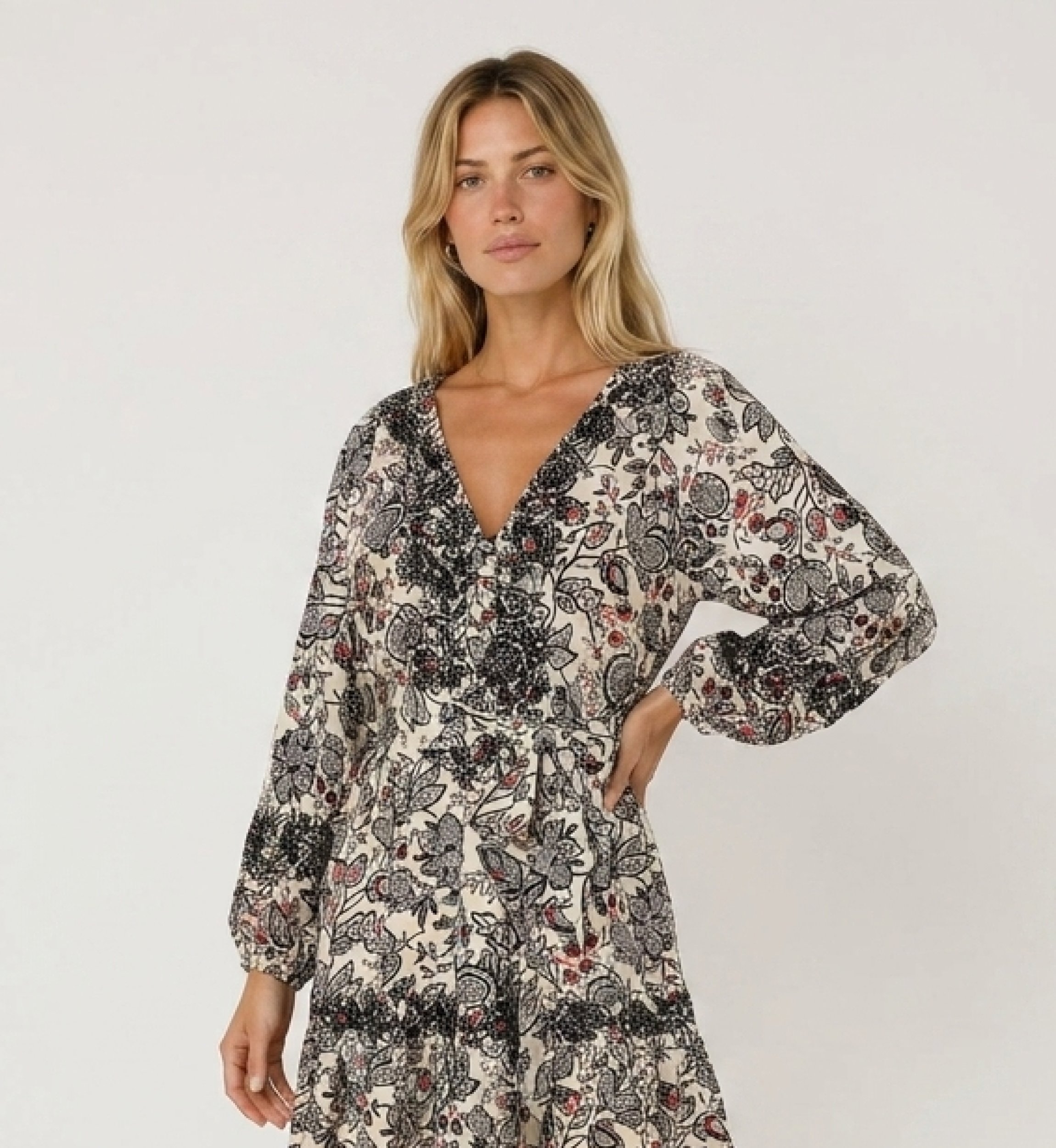 Robe courte crème à motif cachemire noir et rouge, col V, manches longues, jupe étagée, taille nouée, tissu léger, vue côté.