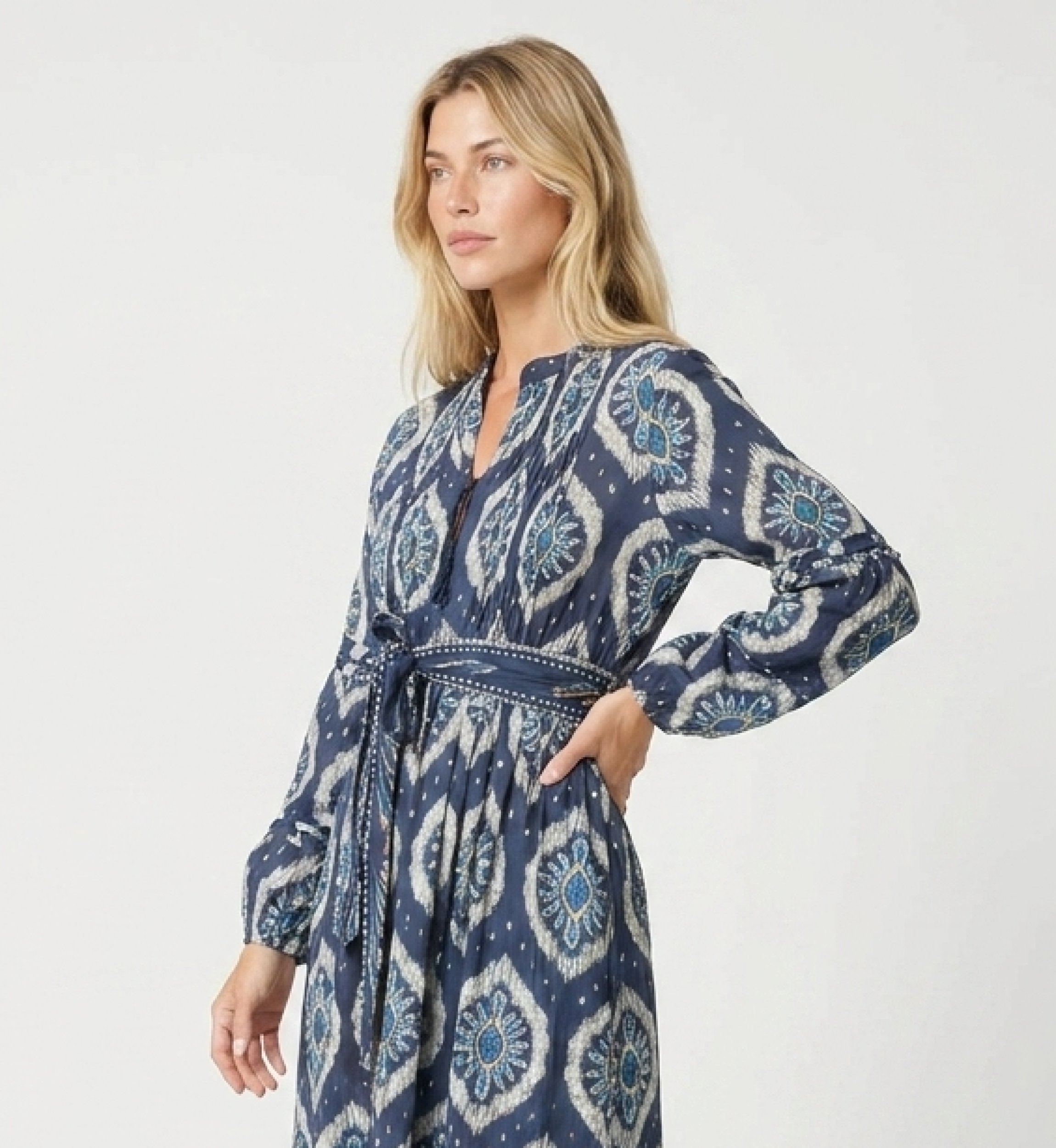 Three-quarter view of a blue and white ikat midi dress with long puff sleeves, tiered skirt, and tie belt.