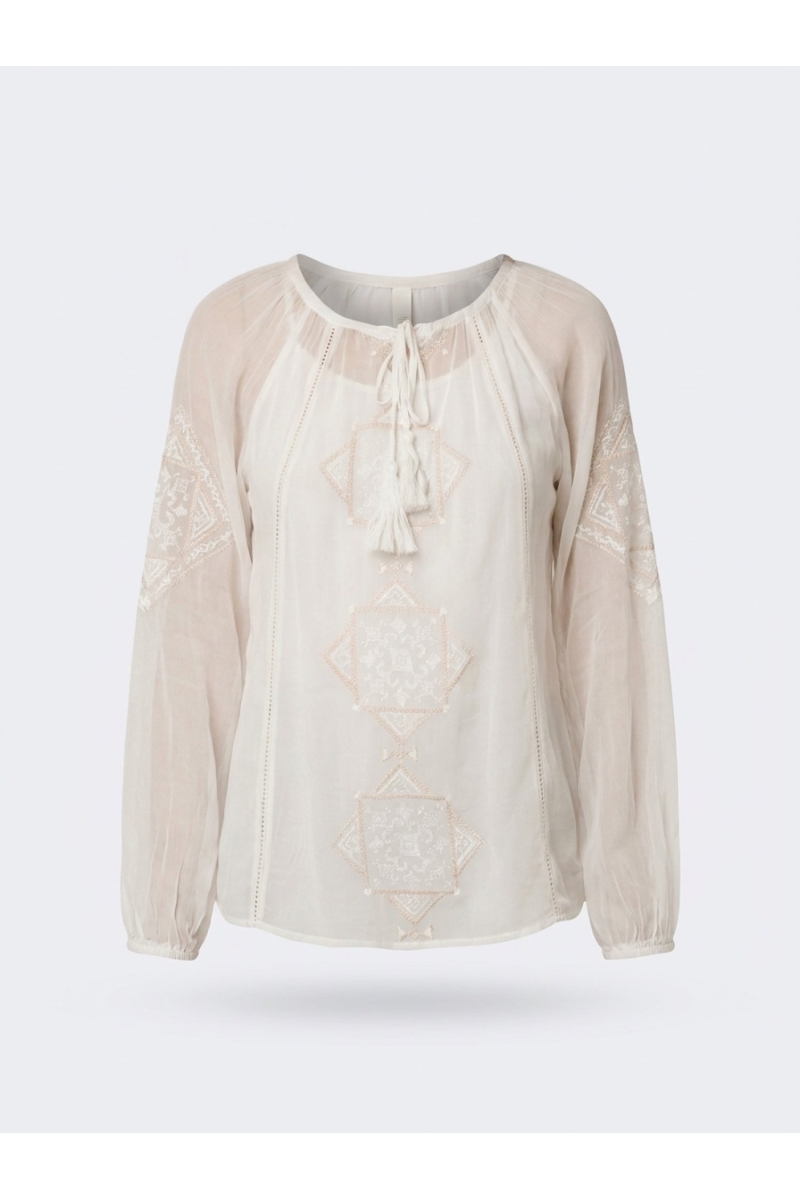 Blusa holgada cruda de manga larga con bordado y cuello anudado, combinada con pantalón negro ancho.